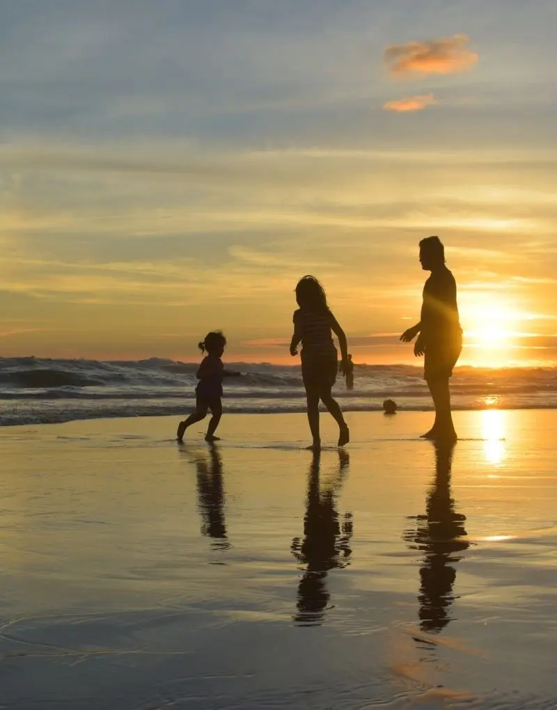 Familie spielt am Meer während eines Sonnenuntergangs
